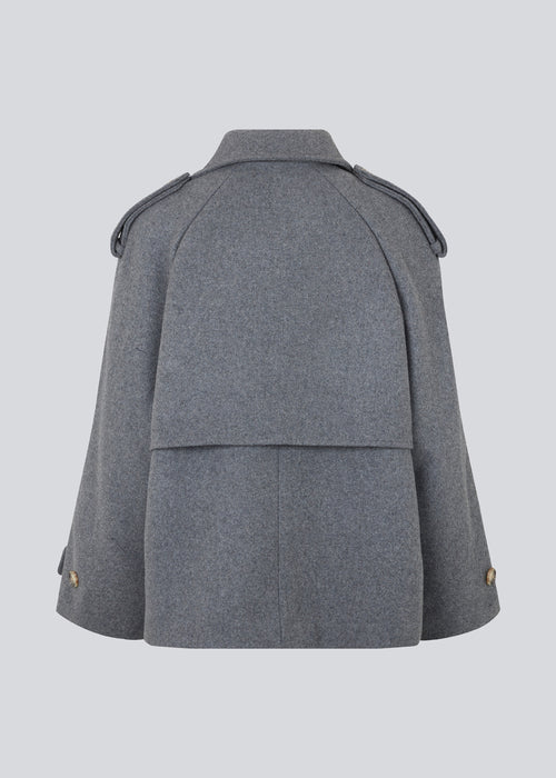 Cropped dobbeltradet uldfrakke med skjulte knapper. EsmundMD jacket i farven Dark Grey Melange har klassiske frakkedetaljer med raglanærmer og bredt bærestykke på ryggen. Med foer. Modellen er 175 cm og har en størrelse S/36 på.