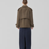 Cropped dobbeltradet uldfrakke i en brun farve med skjulte knapper. EsmundMD jacket har klassiske frakkedetaljer med raglanærmer og bredt bærestykke på ryggen. Med foer. Modellen er 175 cm og har en størrelse S/36 på.