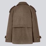 Cropped dobbeltradet uldfrakke i en brun farve med skjulte knapper. EsmundMD jacket har klassiske frakkedetaljer med raglanærmer og bredt bærestykke på ryggen. Med foer. Modellen er 175 cm og har en størrelse S/36 på.