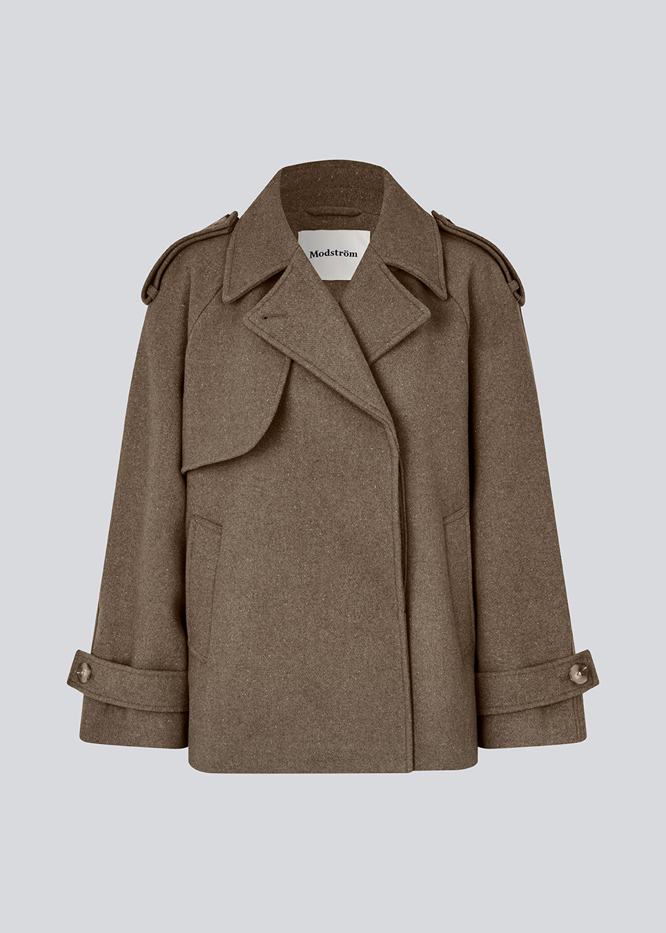 Cropped dobbeltradet uldfrakke i en brun farve med skjulte knapper. EsmundMD jacket har klassiske frakkedetaljer med raglanærmer og bredt bærestykke på ryggen. Med foer. Modellen er 175 cm og har en størrelse S/36 på.