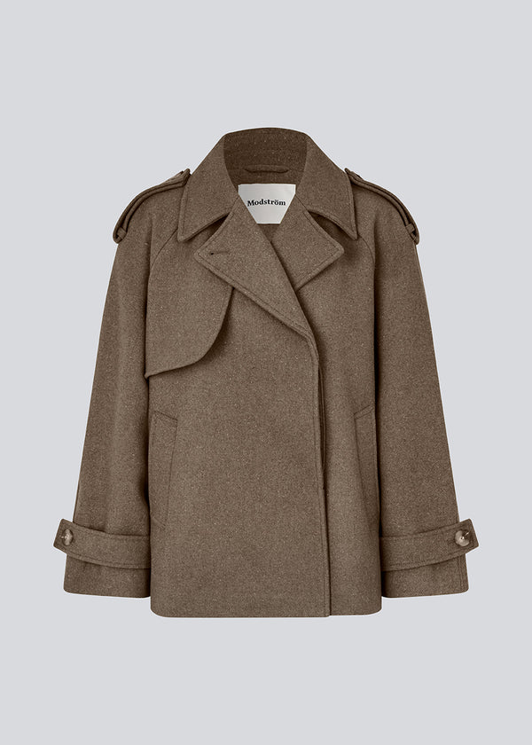Cropped dobbeltradet uldfrakke i en brun farve med skjulte knapper. EsmundMD jacket har klassiske frakkedetaljer med raglanærmer og bredt bærestykke på ryggen. Med foer. Modellen er 175 cm og har en størrelse S/36 på.