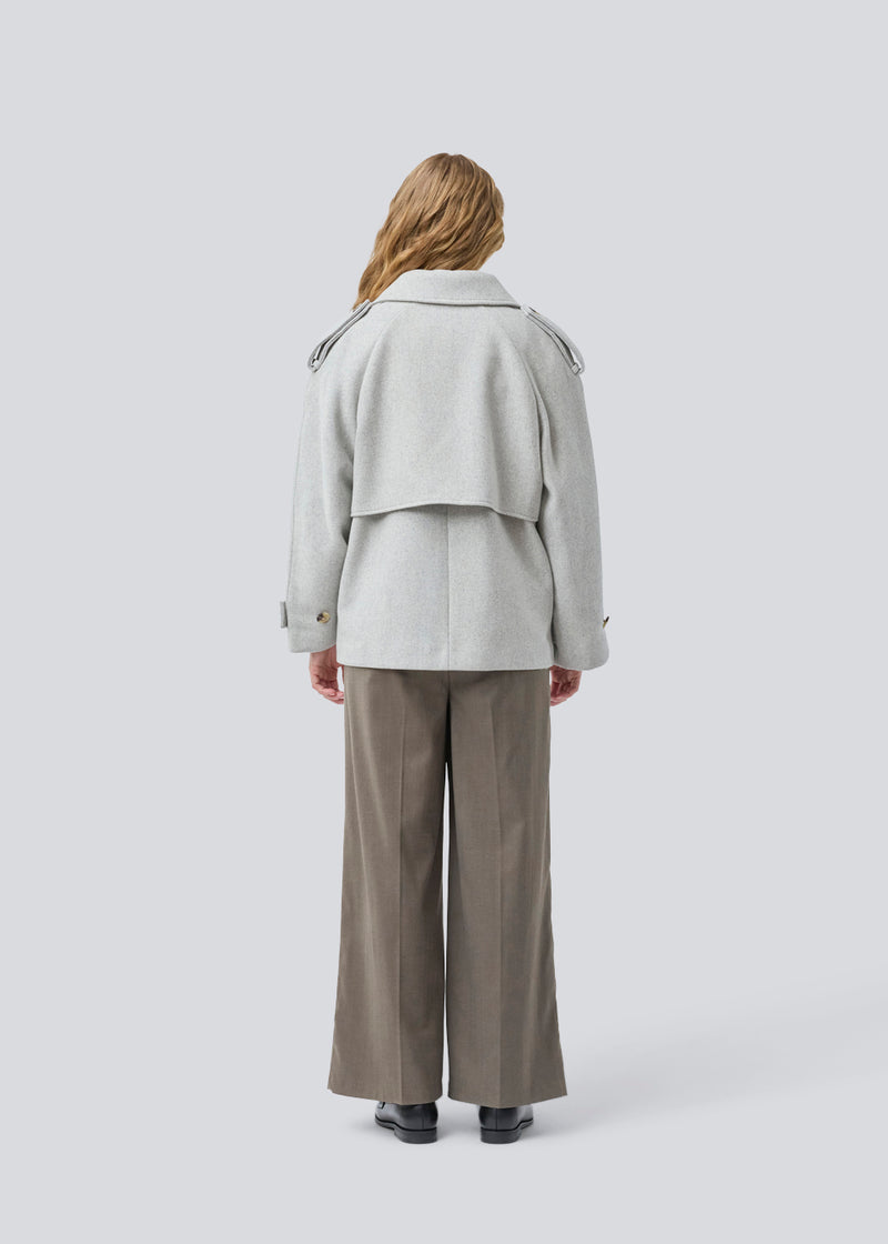 Lysegrå cropped dobbeltradet uldfrakke i lysegrå med skjulte knapper. EsmundMD jacket har klassiske frakkedetaljer med raglanærmer og bredt bærestykke på ryggen. Med foer. Modellen er 175 cm og har en størrelse S/36 på.