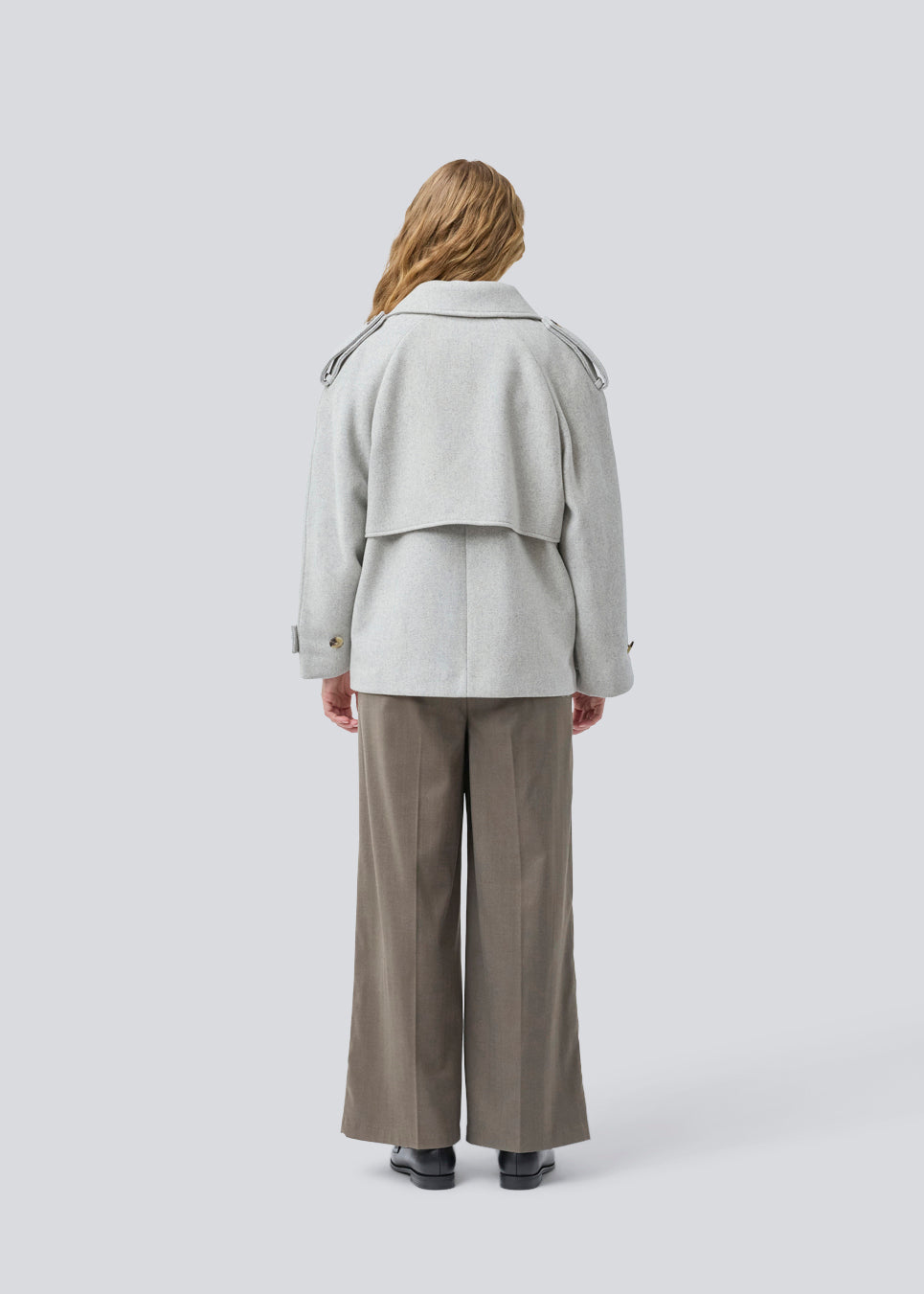 Lysegrå cropped dobbeltradet uldfrakke i lysegrå med skjulte knapper. EsmundMD jacket har klassiske frakkedetaljer med raglanærmer og bredt bærestykke på ryggen. Med foer. Modellen er 175 cm og har en størrelse S/36 på.