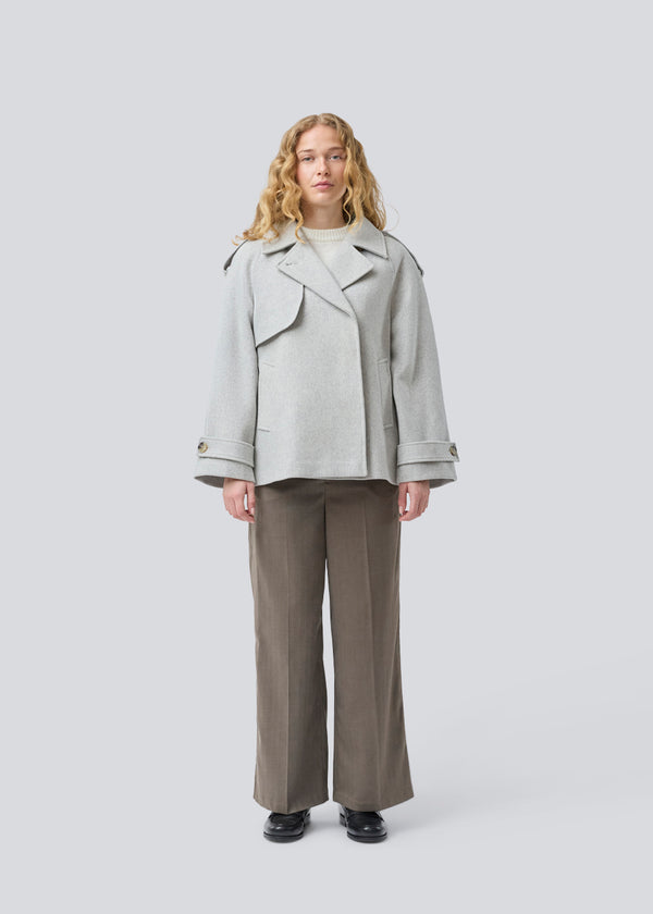 Lysegrå cropped dobbeltradet uldfrakke i lysegrå med skjulte knapper. EsmundMD jacket har klassiske frakkedetaljer med raglanærmer og bredt bærestykke på ryggen. Med foer. Modellen er 175 cm og har en størrelse S/36 på.