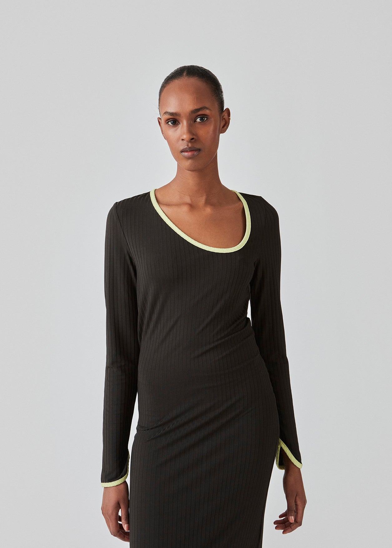 Tætsiddende maxi-kjole i strækbar rib. FaizMD dress har lange ærmer med slids, slids i siden af skørtet og asymmetrisk halsudskæring med kontrasterende kant. Modellen er 175 cm og har en størrelse S/36 på.