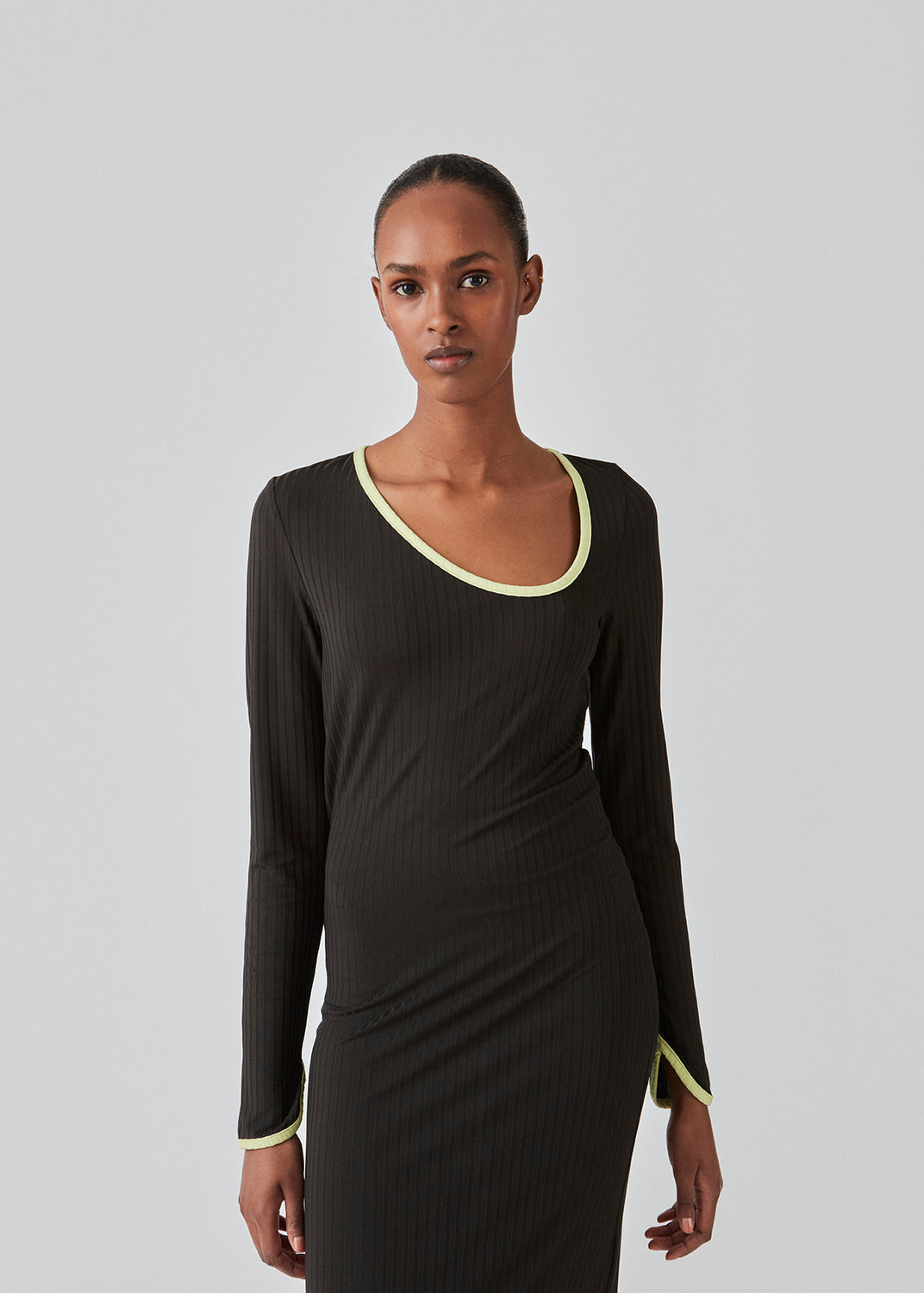 Tætsiddende maxi-kjole i strækbar rib. FaizMD dress har lange ærmer med slids, slids i siden af skørtet og asymmetrisk halsudskæring med kontrasterende kant. Modellen er 175 cm og har en størrelse S/36 på.