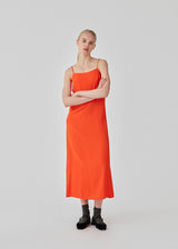 Lang stropkjole i bright cherry i mønstret satin med løs silhuet. FallowMD dress er stylet med tynde stropper. Kjolen er med foer. Modellen er 175 cm og har en størrelse S/36 på.