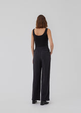 FanyaMD pants i sort har et herre-inspireret look med lige, brede ben, høj talje med lynlåsgylp og knap og elastik bagpå. Dobbeltlæg fo