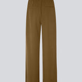 FanyaMD pants i brun har et herre-inspireret look med lige, brede ben, høj talje med lynlåsgylp og knap og elastik bagpå. Dobbeltlæg foran og sidelommer. Modellen er 175 cm og har en størrelse S/36 på.