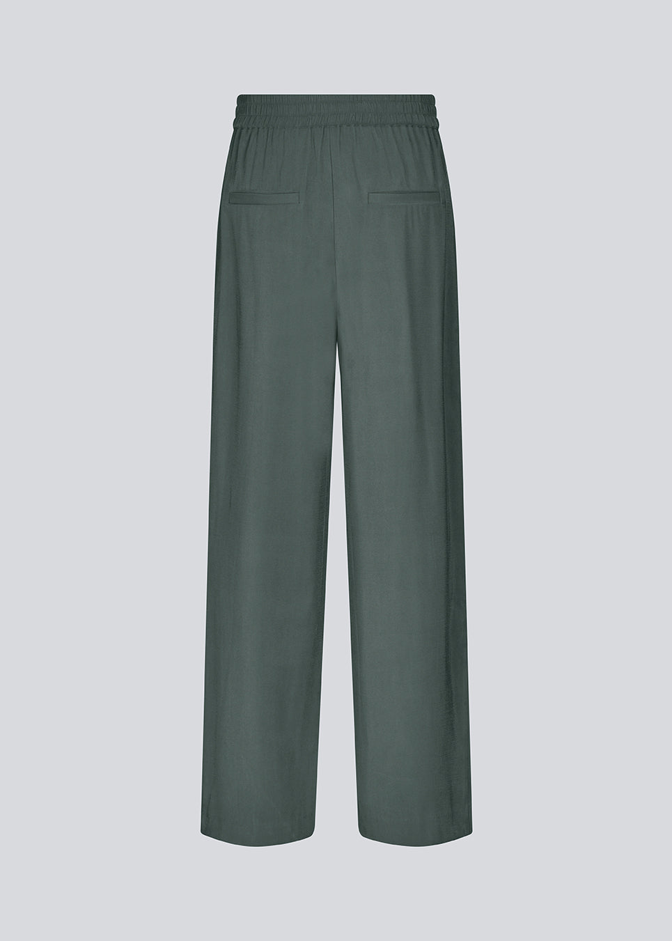 FanyaMD pants i mørkegrøn har et herre-inspireret look med lige, brede ben, høj talje med lynlåsgylp og knap og elastik bagpå. Dobbeltlæg foran og sidelommer. Modellen er 175 cm og har en størrelse S/36 på.