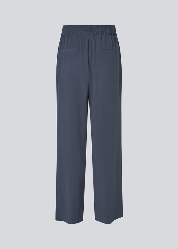 FanyaMD pants har et herre-inspireret look med lige, brede ben, høj talje med lynlåsgylp og knap og elastik bagpå. Dobbeltlæg foran og sidelommer. 