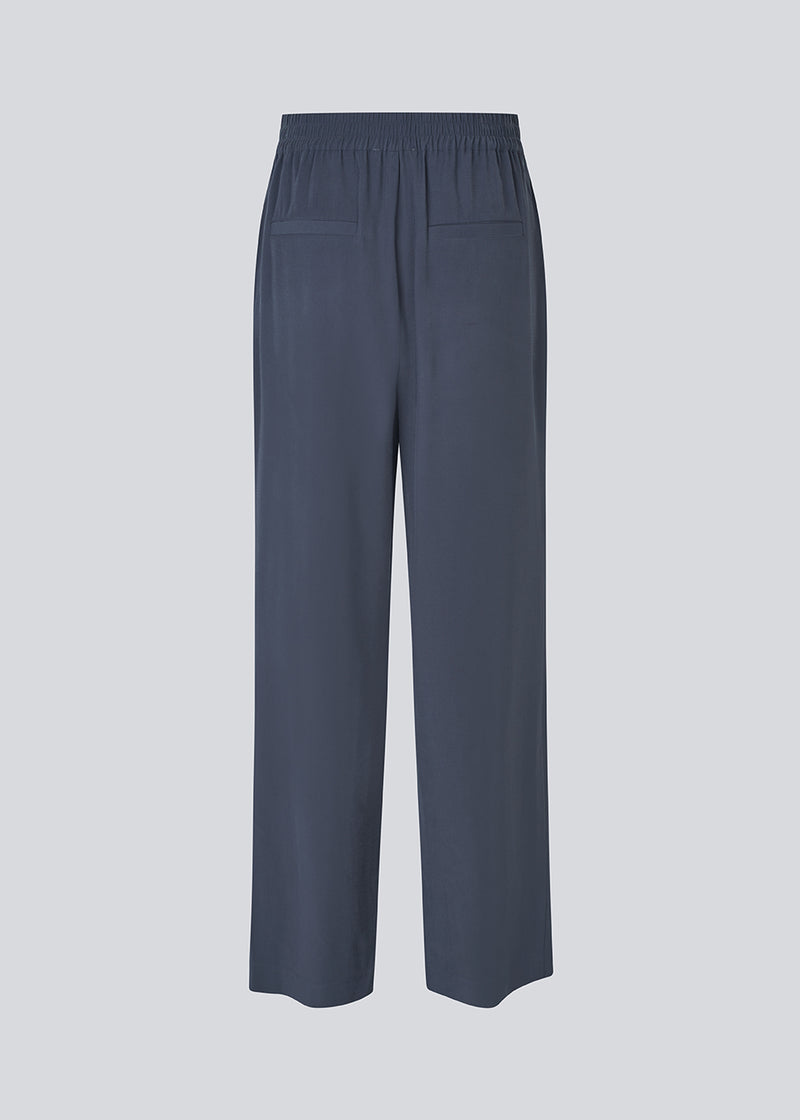 FanyaMD pants har et herre-inspireret look med lige, brede ben, høj talje med lynlåsgylp og knap og elastik bagpå. Dobbeltlæg foran og sidelommer. 