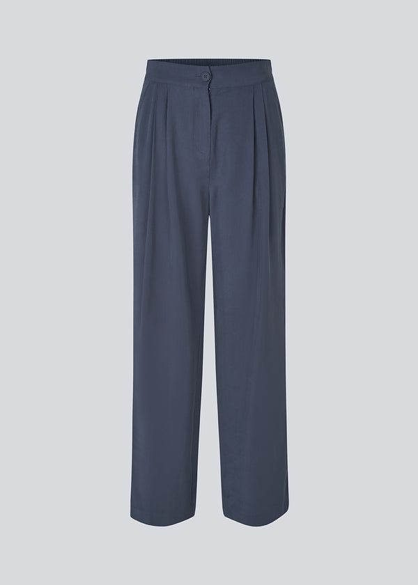 FanyaMD pants har et herre-inspireret look med lige, brede ben, høj talje med lynlåsgylp og knap og elastik bagpå. Dobbeltlæg foran og sidelommer. 