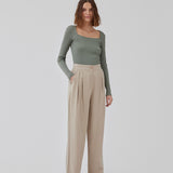 FanyaMD pants i lys beige har et herre-inspireret look med lige, brede ben, høj talje med lynlåsgylp og knap og elastik bagpå. Dobbeltlæg foran og sidelommer. Modellen er 175 cm og har en størrelse S/36 på.