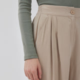 FanyaMD pants i lys beige har et herre-inspireret look med lige, brede ben, høj talje med lynlåsgylp og knap og elastik bagpå. Dobbeltlæg foran og sidelommer. Modellen er 175 cm og har en størrelse S/36 på.
