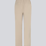 FanyaMD pants i lys beige har et herre-inspireret look med lige, brede ben, høj talje med lynlåsgylp og knap og elastik bagpå. Dobbeltlæg foran og sidelommer. Modellen er 175 cm og har en størrelse S/36 på.