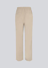 FanyaMD pants i lys beige har et herre-inspireret look med lige, brede ben, høj talje med lynlåsgylp og knap og elastik bagpå. Dobbeltlæg foran og sidelommer. Modellen er 175 cm og har en størrelse S/36 på.