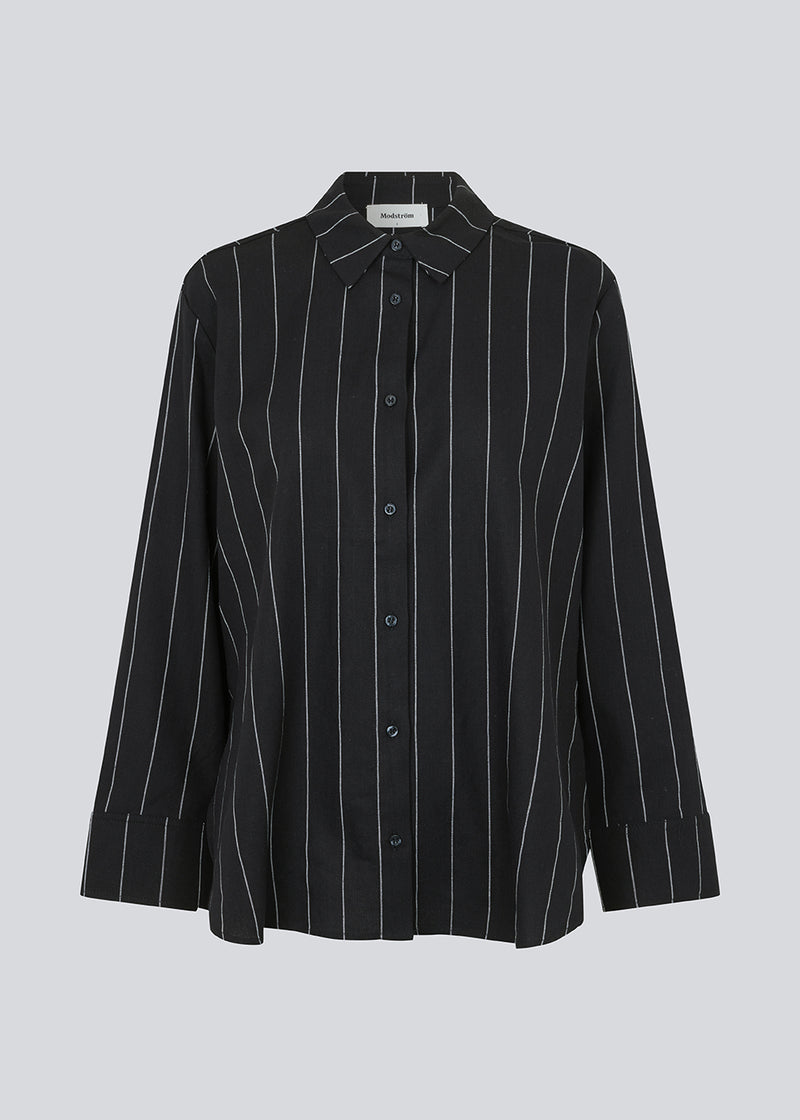Stribet sort skjorte i hørblanding med krave, knapper foran og bærestykke bagpå. FiaMD shirt har en løs pasform med lange brede ærmer. Modellen er 175 cm og har en størrelse S/36 på.