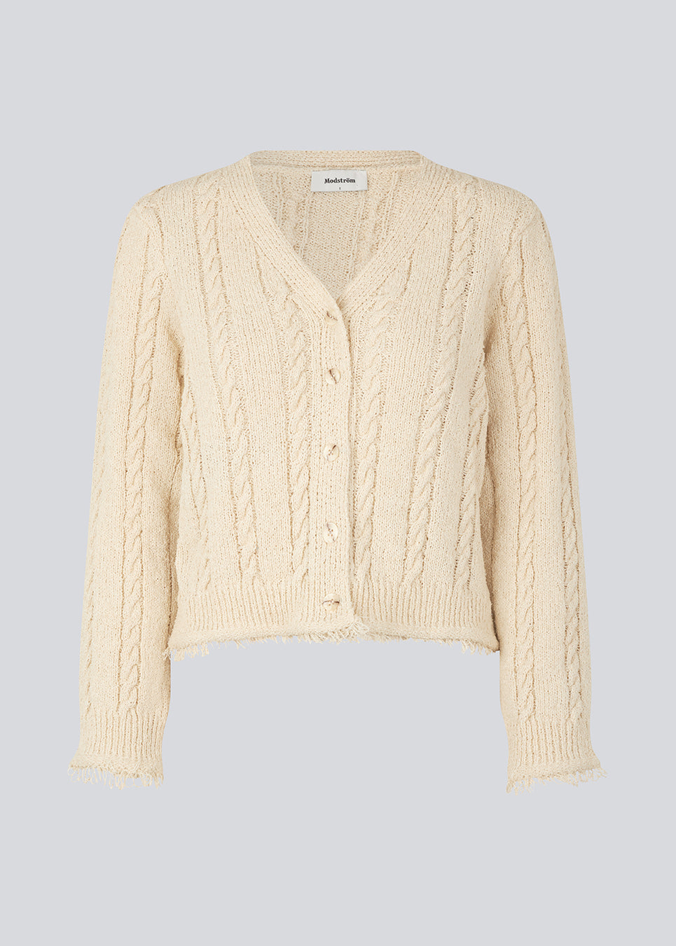 Beige cardigan i kabelstrik med bomuld. Oversized og let cropped pasform med lange ærmer og rå kanter. FinaMD cardigan har v-udskæring og knapper foran. Modellen er 175 cm og har en størrelse S/36 på.