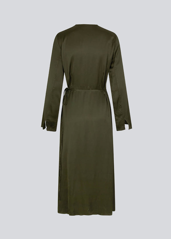 Lang kjole i mørkegrøn i satin af EcoVero viskose-mix. FloreMD wrap dress har v-udskæring og wrap-effekt med tyndt bindebånd. Lange ærmer med slids forneden. 