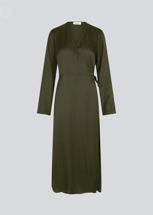 Lang kjole i mørkegrøn i satin af EcoVero viskose-mix. FloreMD wrap dress har v-udskæring og wrap-effekt med tyndt bindebånd. Lange ærmer med slids forneden. 