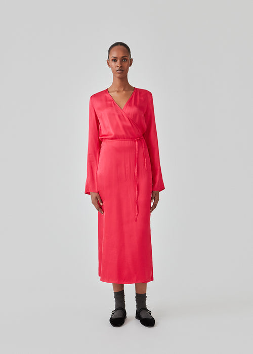 Lang kjole i pink i satin af EcoVero viskose-mix. FloreMD wrap dress har v-udskæring og wrap-effekt med tyndt bindebånd. Lange ærmer med slids forneden. Modellen er 175 cm og har en størrelse S/36 på.
