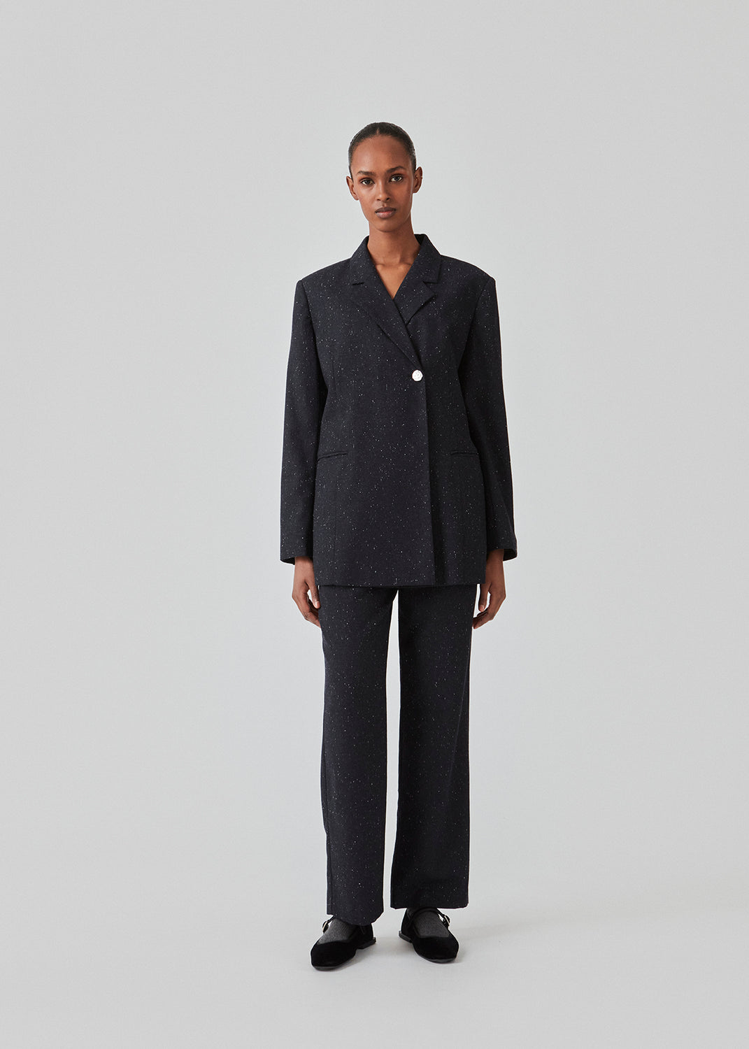 Oversized dobbeltradet blazer med en enkelt synlig knap. FolaMD blazer er lavet i materiale med uld og små farvede nister. Del af sæt, køb bukserne her: FolaMD. Modellen er 175 cm og har en størrelse S/36 på.