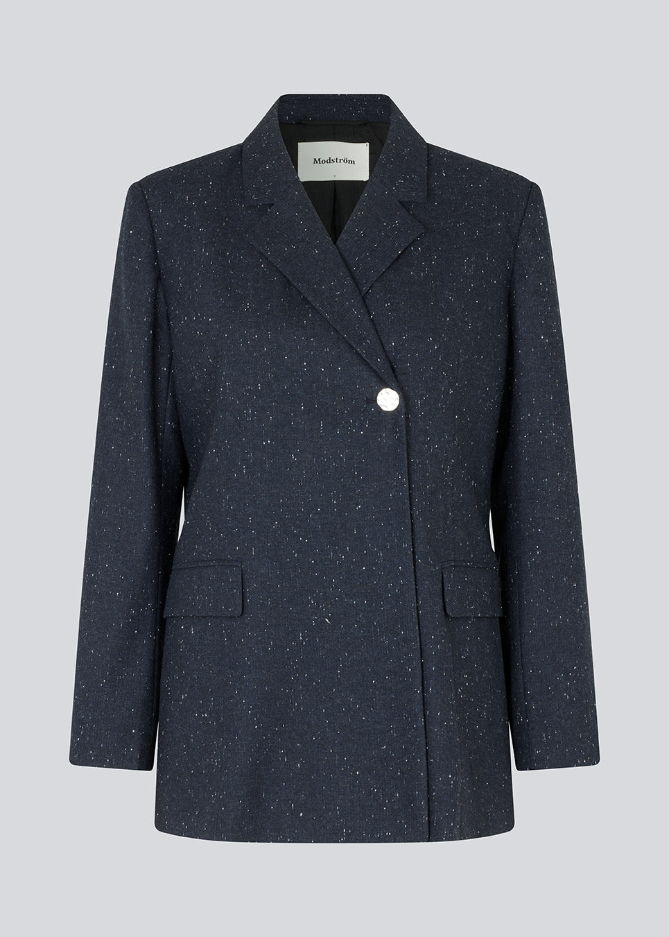 Oversized dobbeltradet blazer med en enkelt synlig knap. FolaMD blazer er lavet i materiale med uld og små farvede nister. Del af sæt, køb bukserne her: FolaMD. Modellen er 175 cm og har en størrelse S/36 på.
