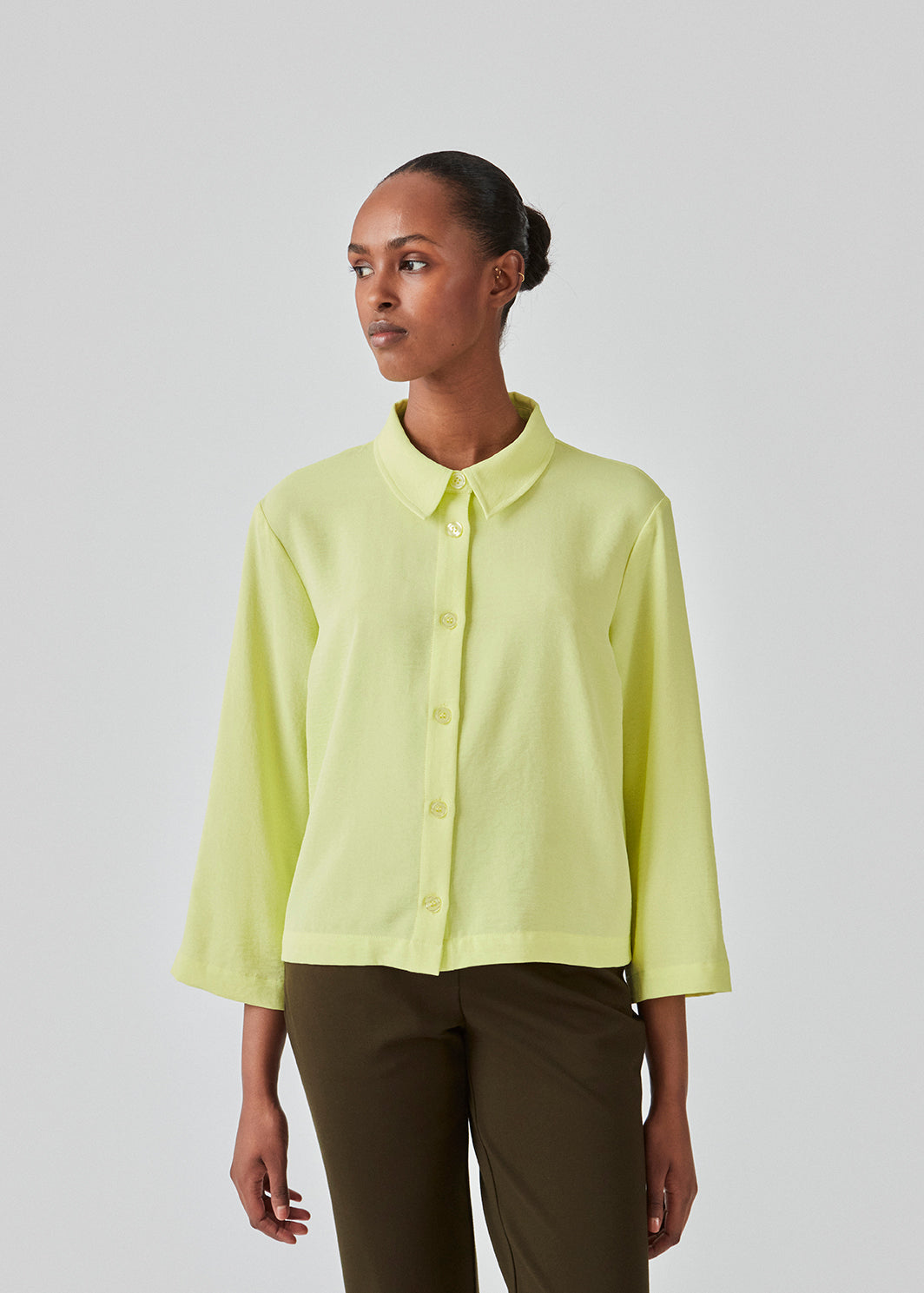 Afkortet skjorte i lys gul med løs og afslappet pasform. FredaMD shirt har krave og knaplukning fortil, samt 3/4 lange brede ærmer. Modellen er 175 cm og har en størrelse S/36 på.