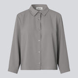 Afkortet skjorte i grå med løs og afslappet pasform. FredaMD shirt har krave og knaplukning fortil, samt 3/4 lange brede ærmer. Modellen er 175 cm og har en størrelse S/36 på.