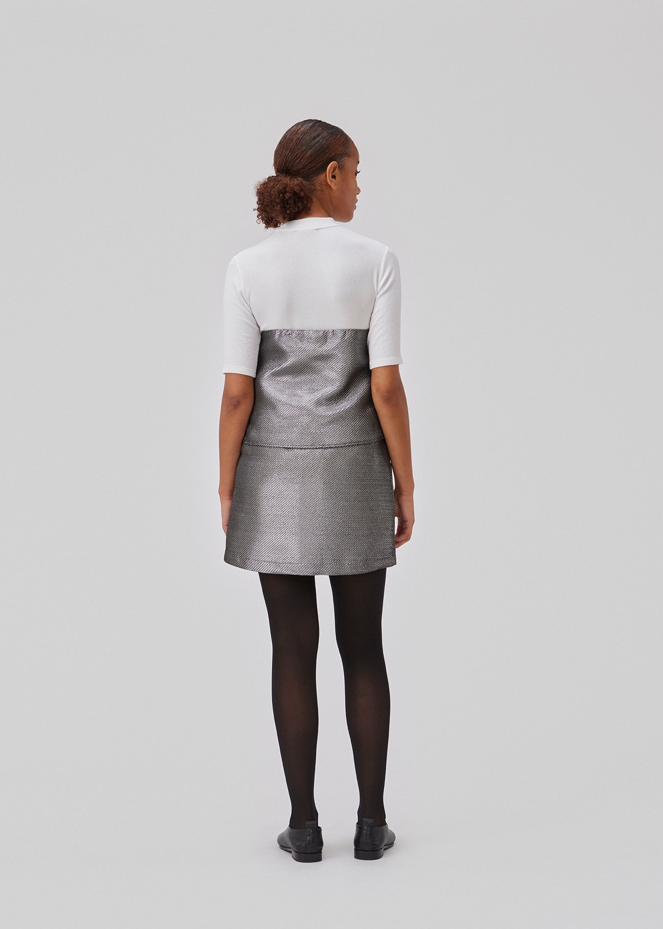 GabbieMD skirt er skåret i en mini-lang silhuet med høj talje og skjult lynlås i stuktureret og skinndende materiale. Med foer. Modellen er 175 cm og har en størrelse S/36 på