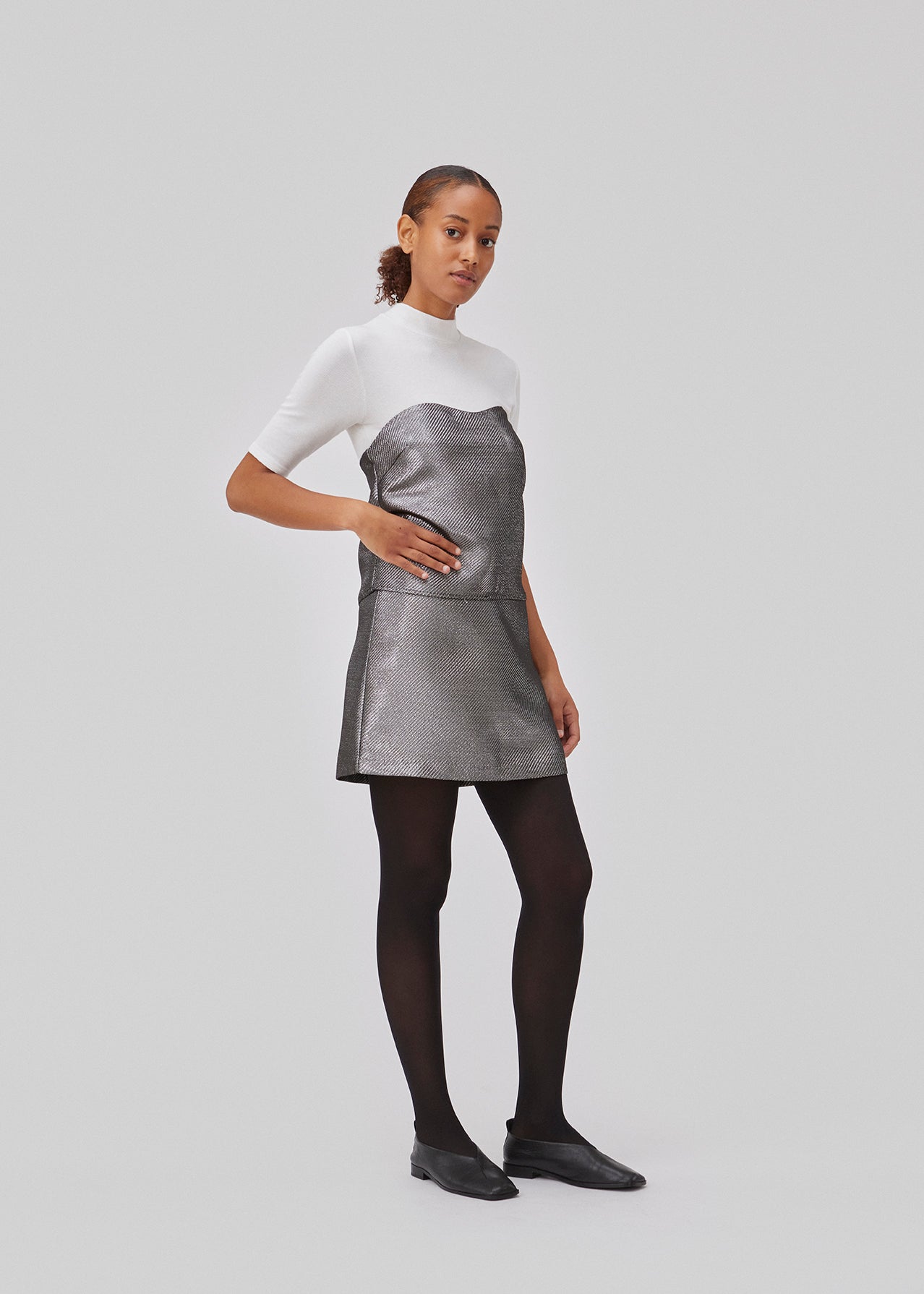 GabbieMD skirt er skåret i en mini-lang silhuet med høj talje og skjult lynlås i stuktureret og skinndende materiale. Med foer. Modellen er 175 cm og har en størrelse S/36 på