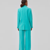 Gale pants i turkis har et klassisk design. Buksen har lige, vide ben med pressefolder som skaber et elegant udtryk. Modellen er 175 cm og har en størrelse S/36 på. Indersøm (S/36): 83 cm Bukserne forlænges med 0,5 cm for hver størrelse.