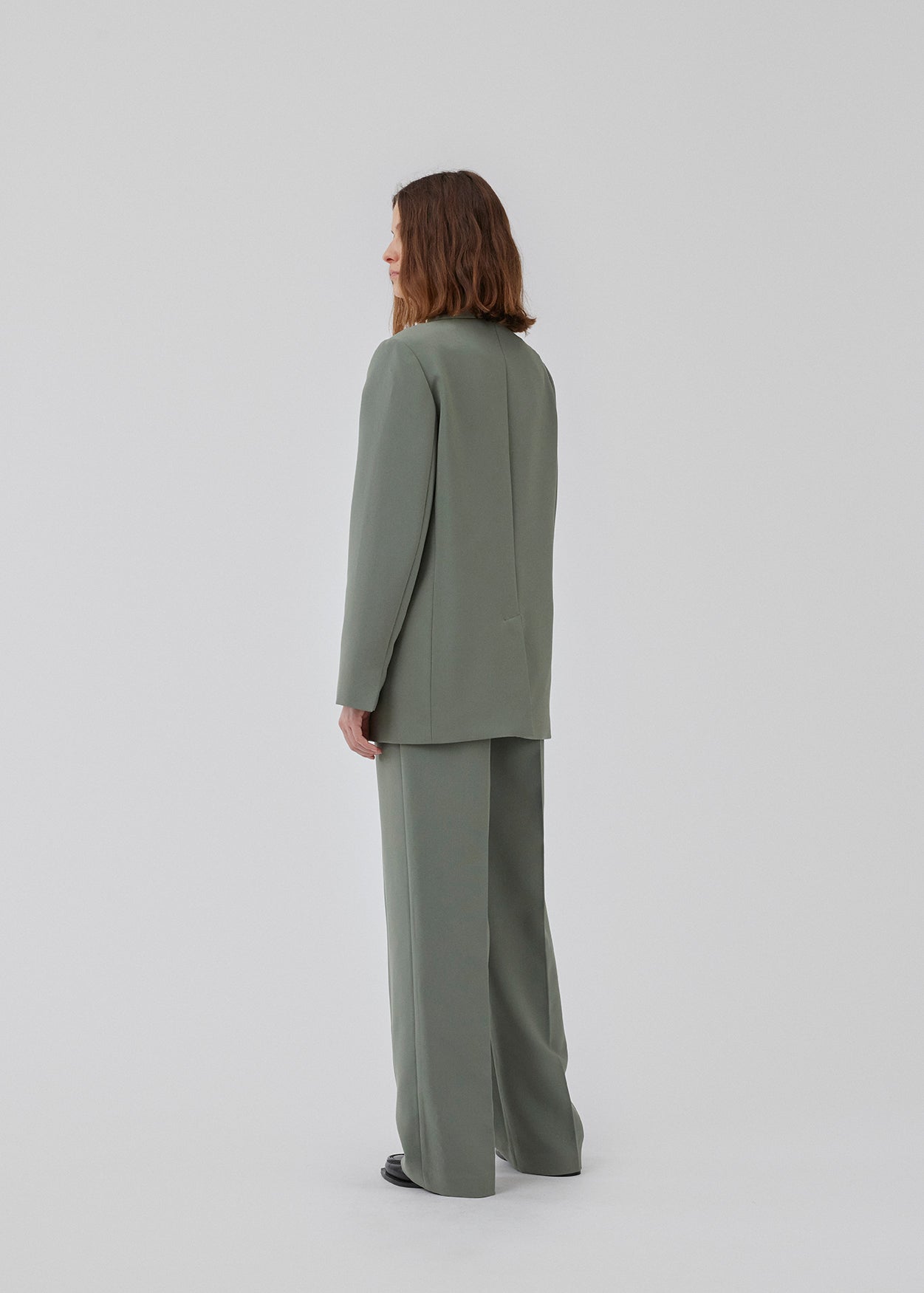 Gale pants i grøn har et klassisk design. Buksen har lige, vide ben med pressefolder som skaber et elegant udtryk. Modellen er 175 cm og har en størrelse S/36 på. Indersøm (S/36): 83 cm Bukserne forlænges med 0,5 cm for hver størrelse.