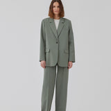 Gale pants i grøn har et klassisk design. Buksen har lige, vide ben med pressefolder som skaber et elegant udtryk. Modellen er 175 cm og har en størrelse S/36 på. Indersøm (S/36): 83 cm Bukserne forlænges med 0,5 cm for hver størrelse.