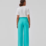 Gale pants i turkis har et klassisk design. Buksen har lige, vide ben med pressefolder som skaber et elegant udtryk. Modellen er 175 cm og har en størrelse S/36 på. Indersøm (S/36): 83 cm Bukserne forlænges med 0,5 cm for hver størrelse.