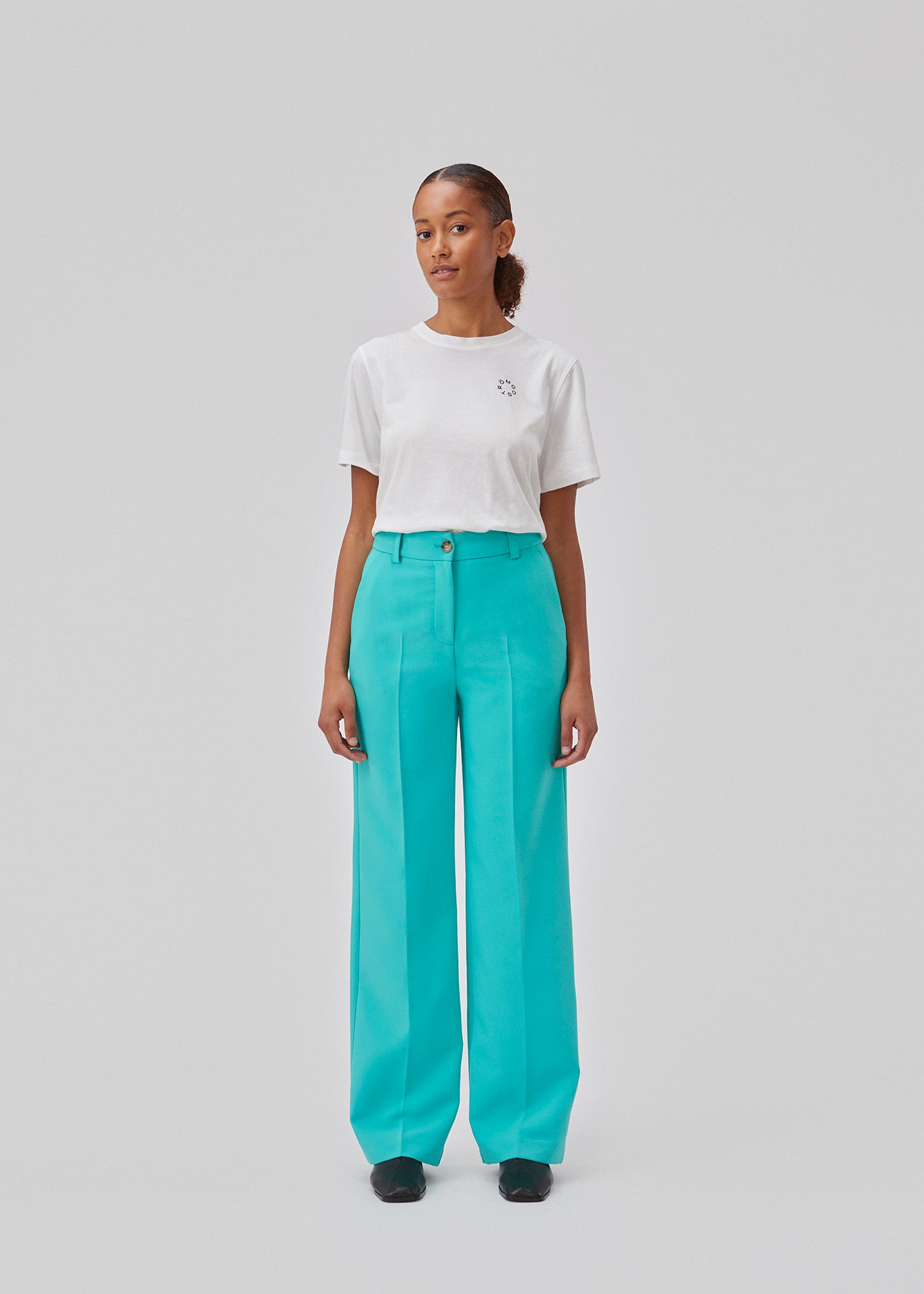 Gale pants i turkis har et klassisk design. Buksen har lige, vide ben med pressefolder som skaber et elegant udtryk. Modellen er 175 cm og har en størrelse S/36 på. Indersøm (S/36): 83 cm Bukserne forlænges med 0,5 cm for hver størrelse.