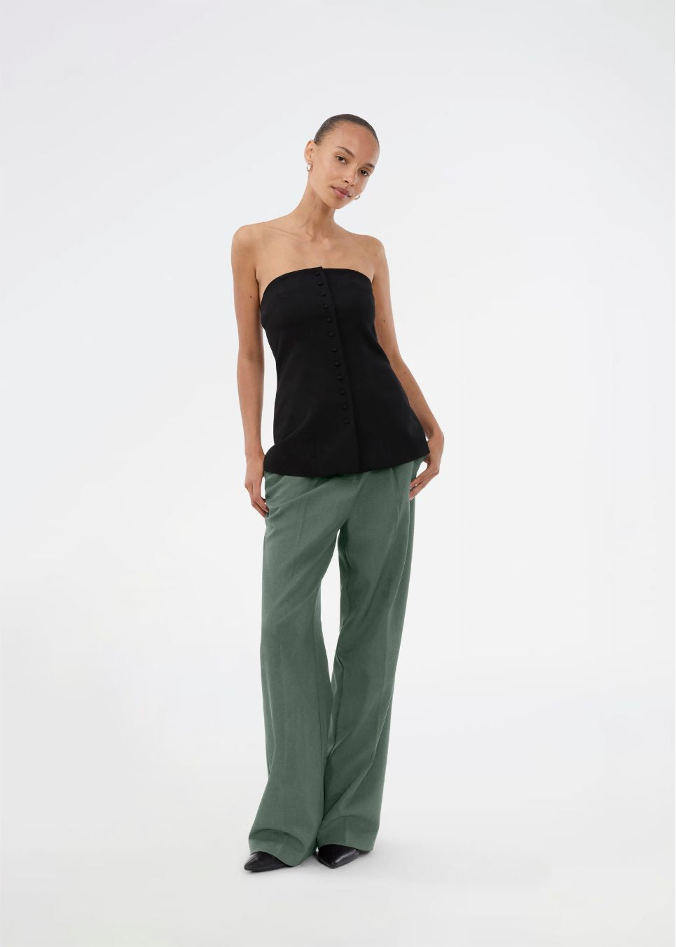 Gale pants i mørkegrøn har et klassisk design. Buksen har lige, vide ben med pressefolder som skaber et elegant udtryk. Modellen er 175 cm og har en størrelse S/36 på.&nbsp;