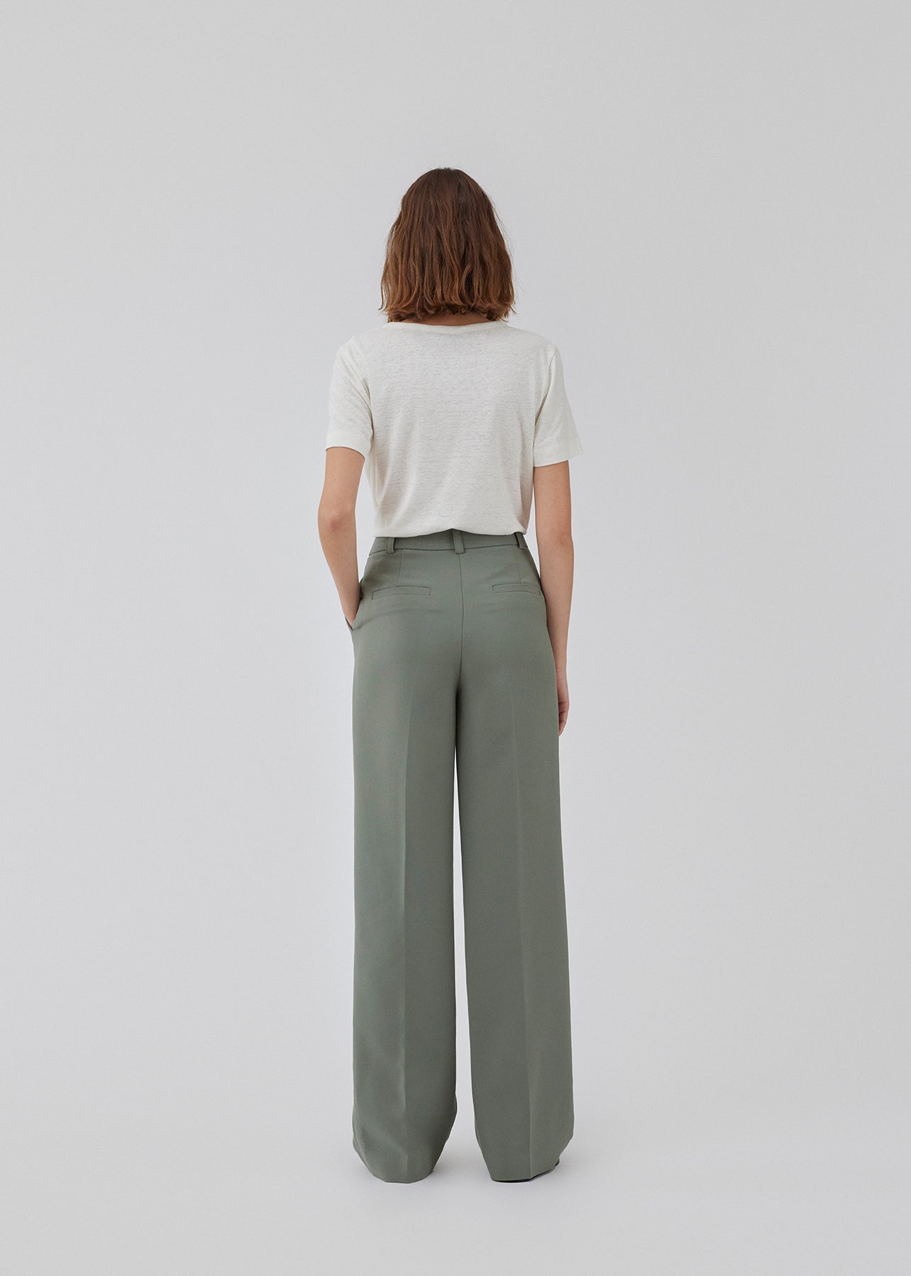 Gale pants i grøn har et klassisk design. Buksen har lige, vide ben med pressefolder som skaber et elegant udtryk. Modellen er 175 cm og har en størrelse S/36 på. Indersøm (S/36): 83 cm Bukserne forlænges med 0,5 cm for hver størrelse.