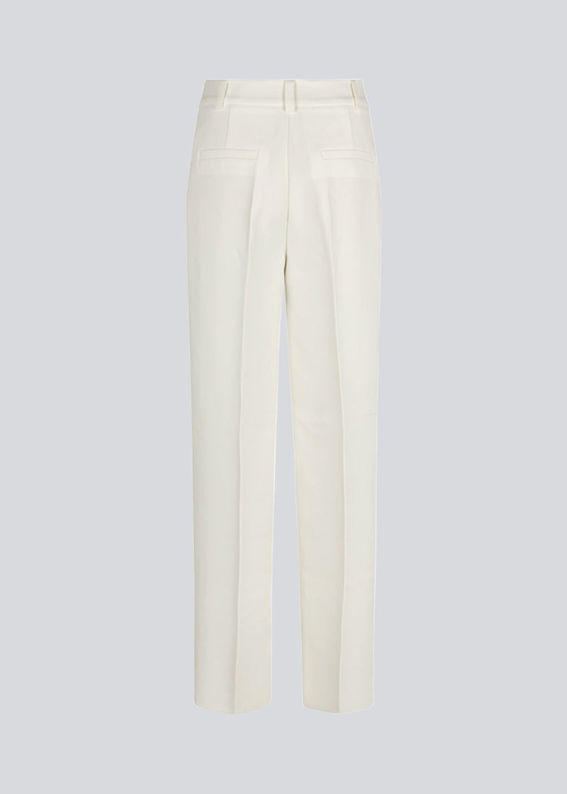 Gale pants i hvid har et klassisk design. Buksen har lige, vide ben med pressefolder som skaber et elegant udtryk. Modellen er 175 cm og har en størrelse S/36 på. Indersøm (S/36): 83 cm Bukserne forlænges med 0,5 cm for hver størrelse.
