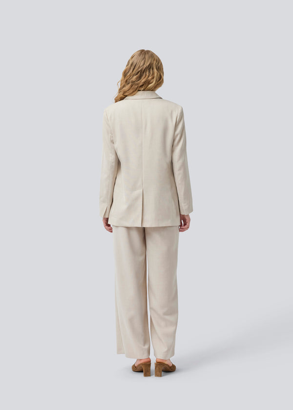 GaleMD 2 blazer i beige melange har det klassiske og velkendte Gale-design, men i en lettere kvalitet. Blazeren har knaplukning fortil og en brystlomme i venstre side. Modellen er 175 cm og har en størrelse S/36 på.