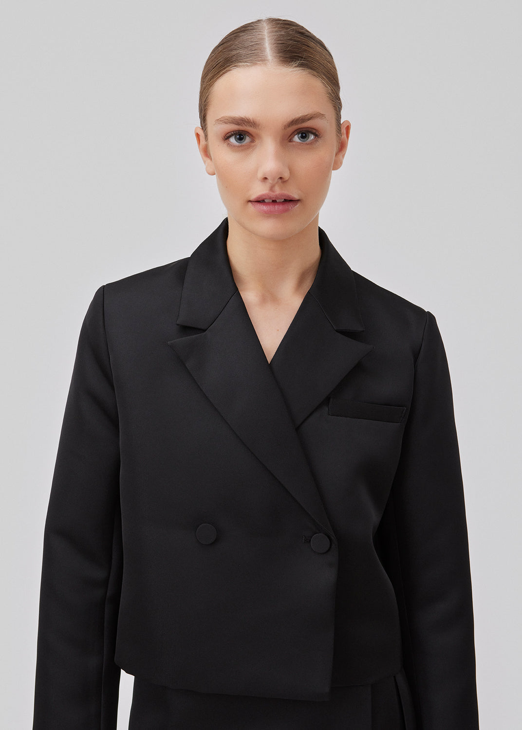 Cropped, dobbeltradet blazer i tung satin. GavinMD blazer har krave og revers, stofbetrukne knapper foran og slidser ved manchetterne. Modellen er 175 cm og har en størrelse S/36 på.  Shop matchende neder