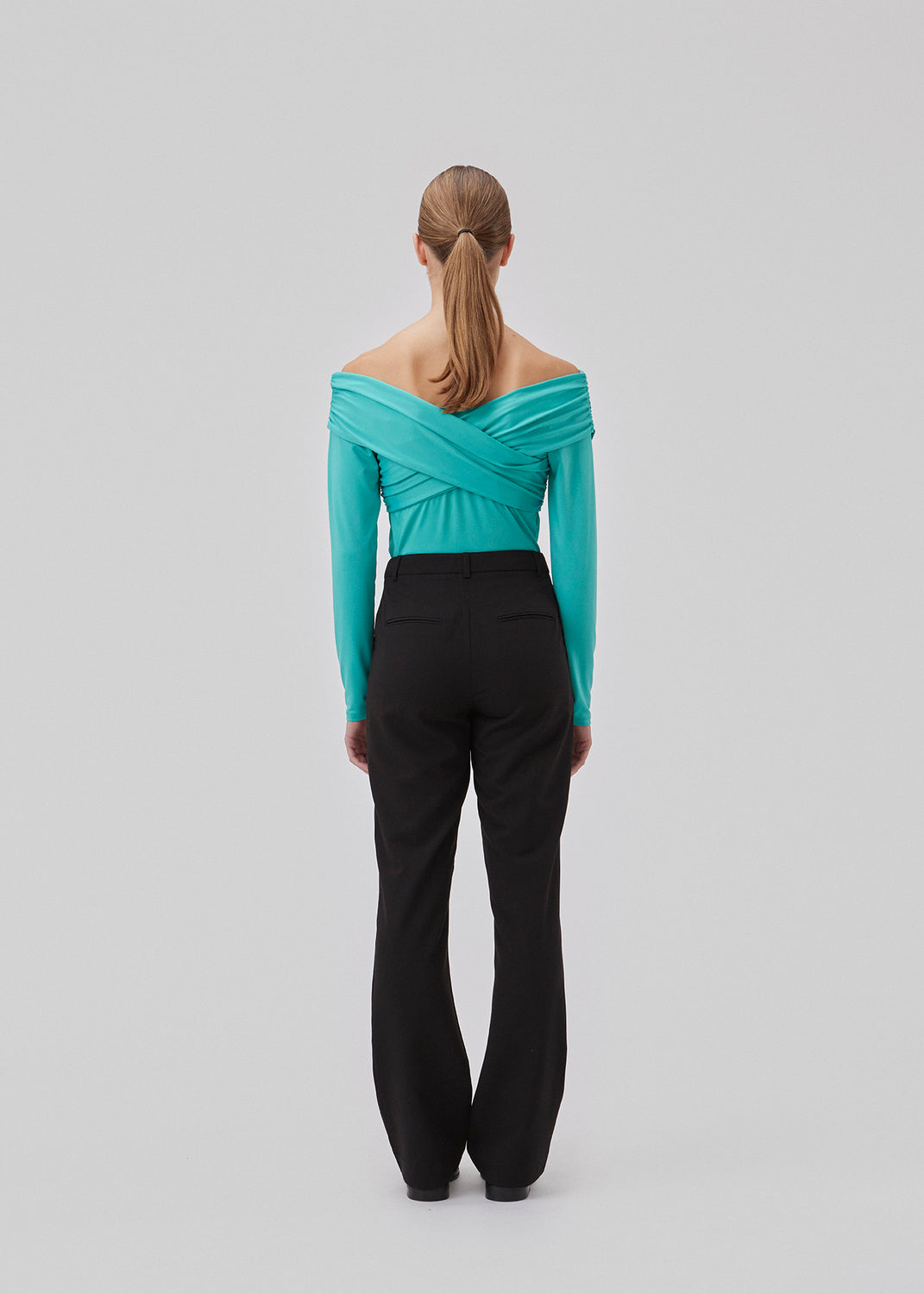 Langærmet top i turkis i blød kvalitet. GeorgiaMD wrap top har en smal silhuet og let off-shoulder-effekt med draperet wrap-look foroven. Modellen er 175 cm og har en størrelse S/36 på.