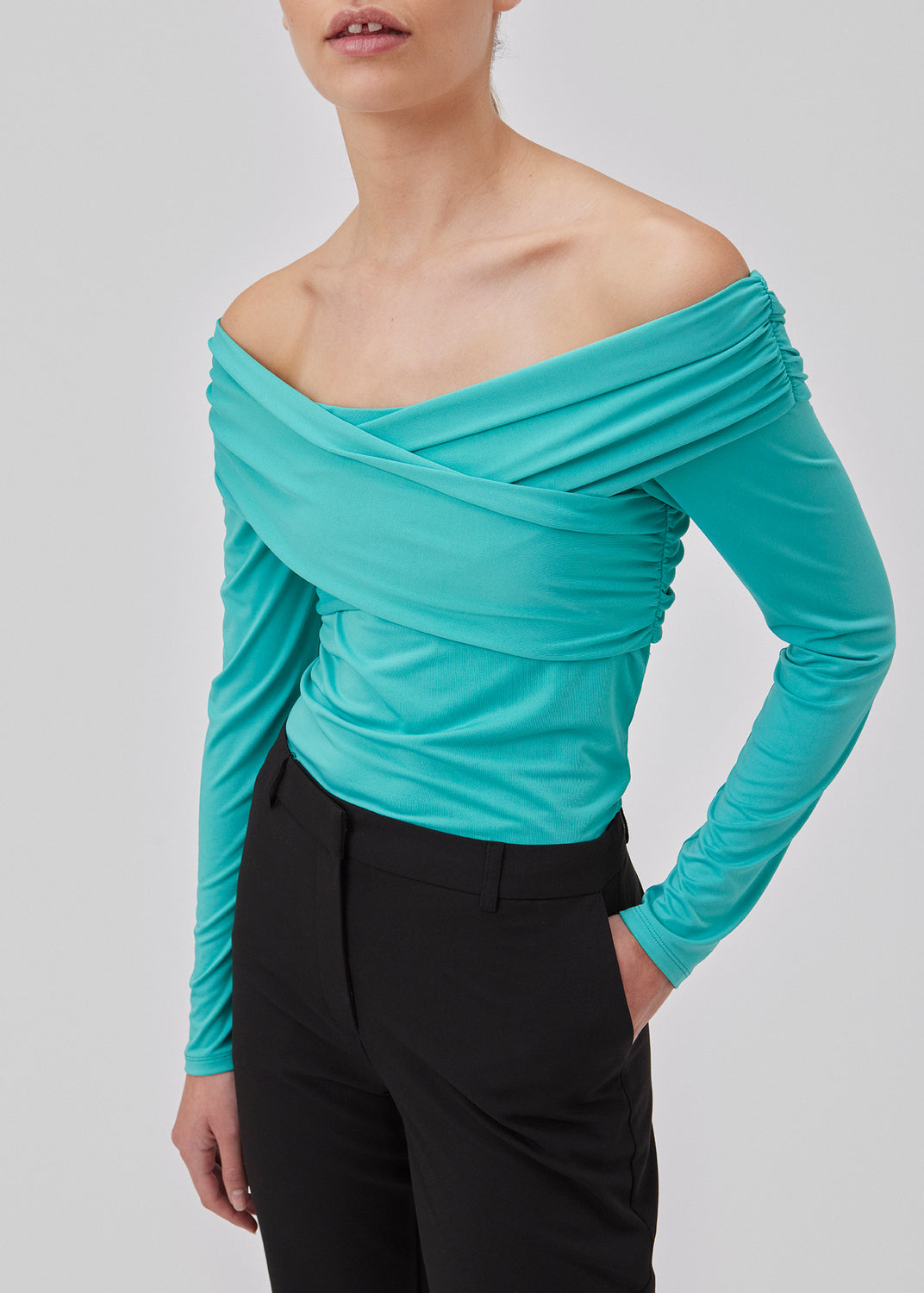 Langærmet top i turkis i blød kvalitet. GeorgiaMD wrap top har en smal silhuet og let off-shoulder-effekt med draperet wrap-look foroven. Modellen er 175 cm og har en størrelse S/36 på.
