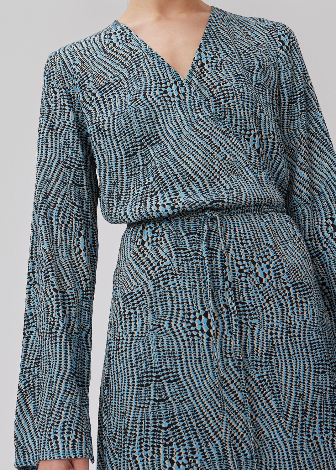 Printet kjole i midi længde. GladstoneMD print dress har wrap-effekt med smalt bindebånd i taljen og v-udskæring i halsen. Lange ærmer med slids. Modellen er 175 cm og har en størrelse S/36 på.