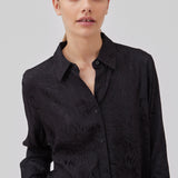 Skjorte i sort i mønstret satin med en let cropped længde. GraceyMD shirt har en løs pasform med lange ærmer, manchet, krave og knapper foran. Modellen er 175 cm og har en størrelse S/36 på.