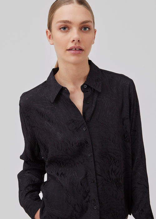 Skjorte i sort i mønstret satin med en let cropped længde. GraceyMD shirt har en løs pasform med lange ærmer, manchet, krave og knapper foran. Modellen er 175 cm og har en størrelse S/36 på.