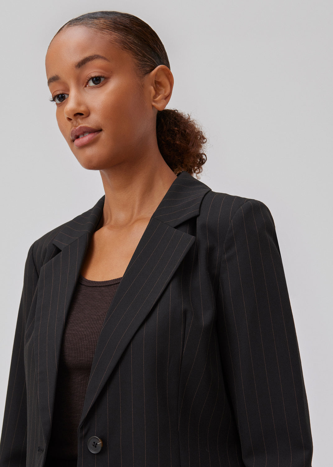 Figursyet blazer i vævet kvalitet med let stretch. GraysonMD blazer er enkeltradet med meget rundede kanter foran, samt en bagside der er en smule længere og uden slids. Slids ved ærmerne. Modellen er 175 cm og har en størrelse S/36 på.