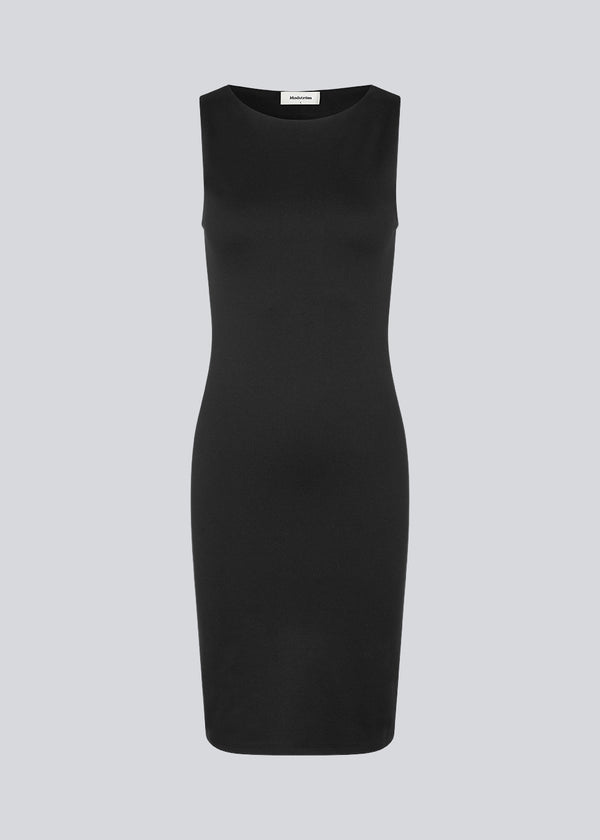 Tætsiddende kjole i sort med høj bådudskæring. HakanMD dress er ærmeløs og har en længde, der går til knæene.