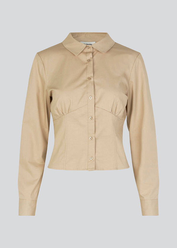 Figursyet skjorte i beige i vævet bomuldskvalitet med krave, knapper foran og lange ærmer med manchet. HarrisonMD shirt har indsnit og skæring under brystet for et korset-inspireret look. Modellen er 175 cm og har en størrelse S/36 på.